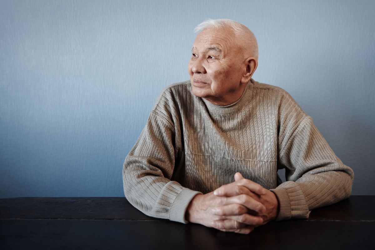 Older aisan man looking out a window